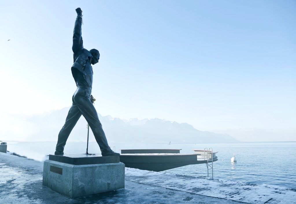 gray metal statue of man raising hand near dock